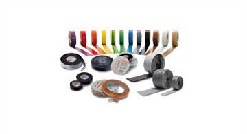 Mehrere Rollen Klebeband in verschiedenen Farben und Materialien, sortiert und ausgerollt auf einer weißen Fläche.